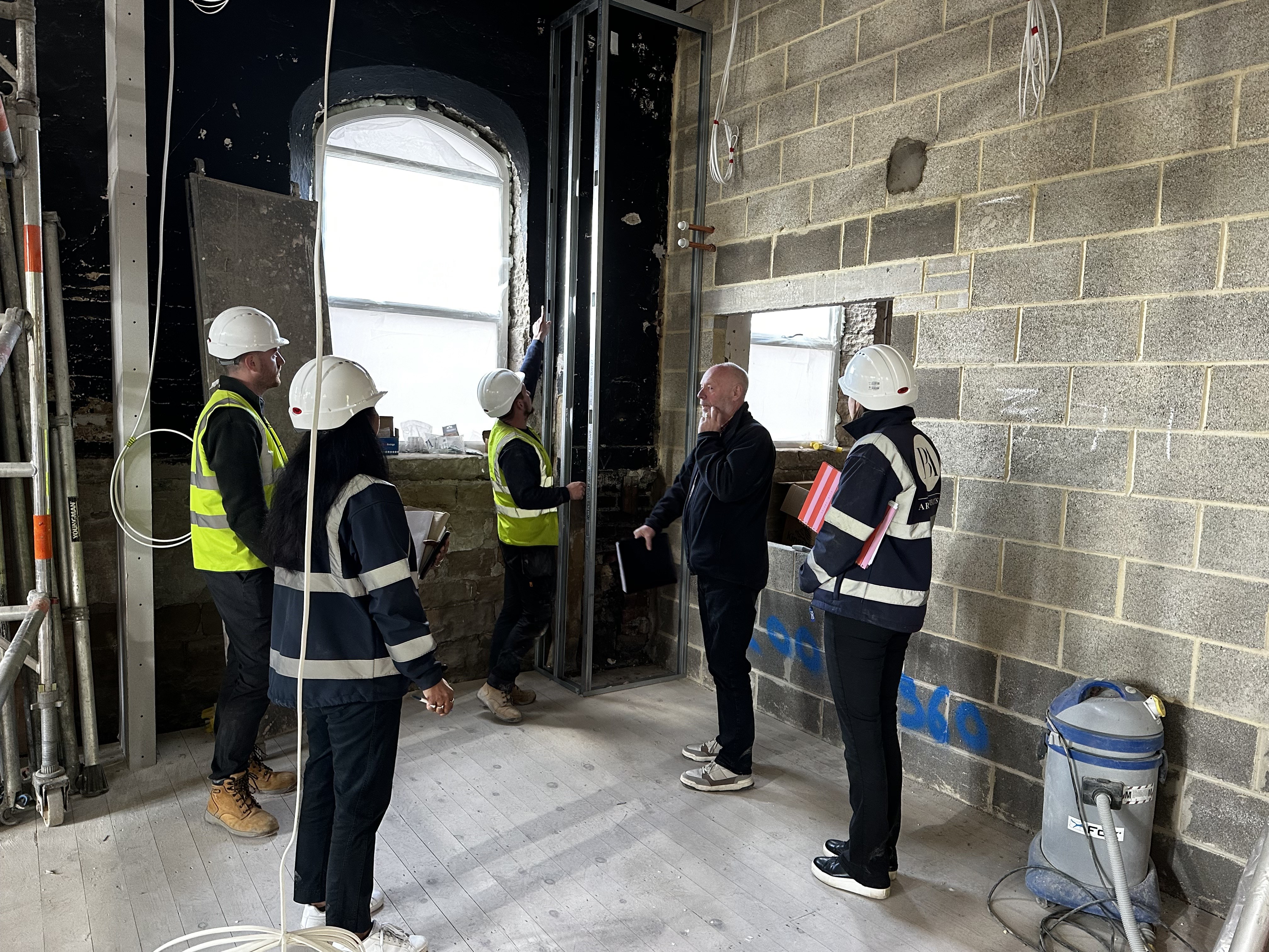 Mick Cooper, the architects and the contractors standing in what will be Studio B with the kitchen hatch visible behind.
